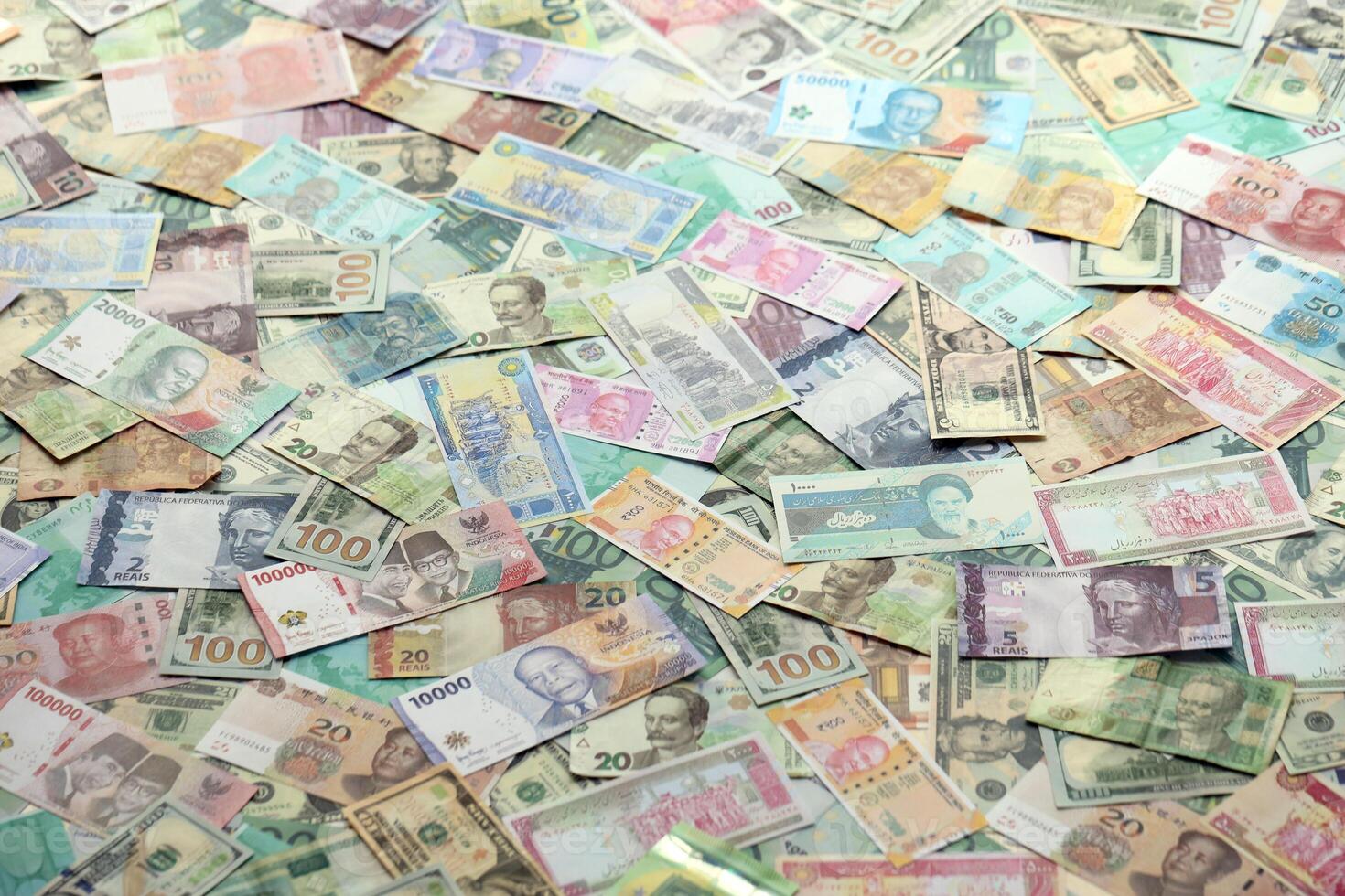 Many banknotes of different currency. Background of big amount of random money bills photo