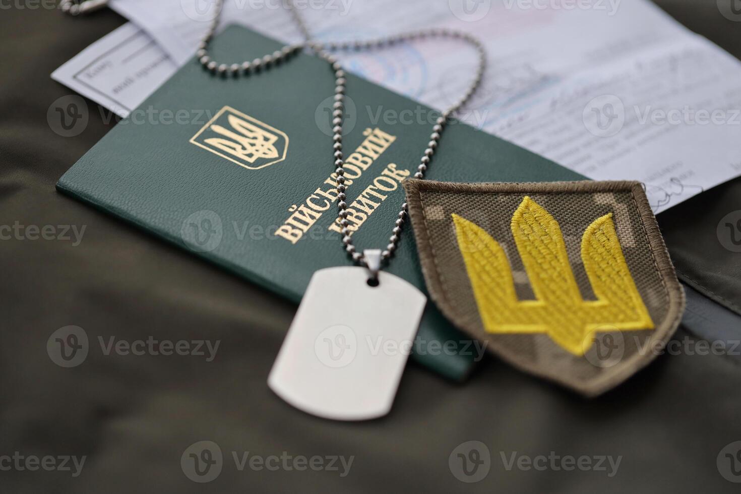 Military token or army ID ticket with mobilization notice lies on green ukrainian military uniform photo