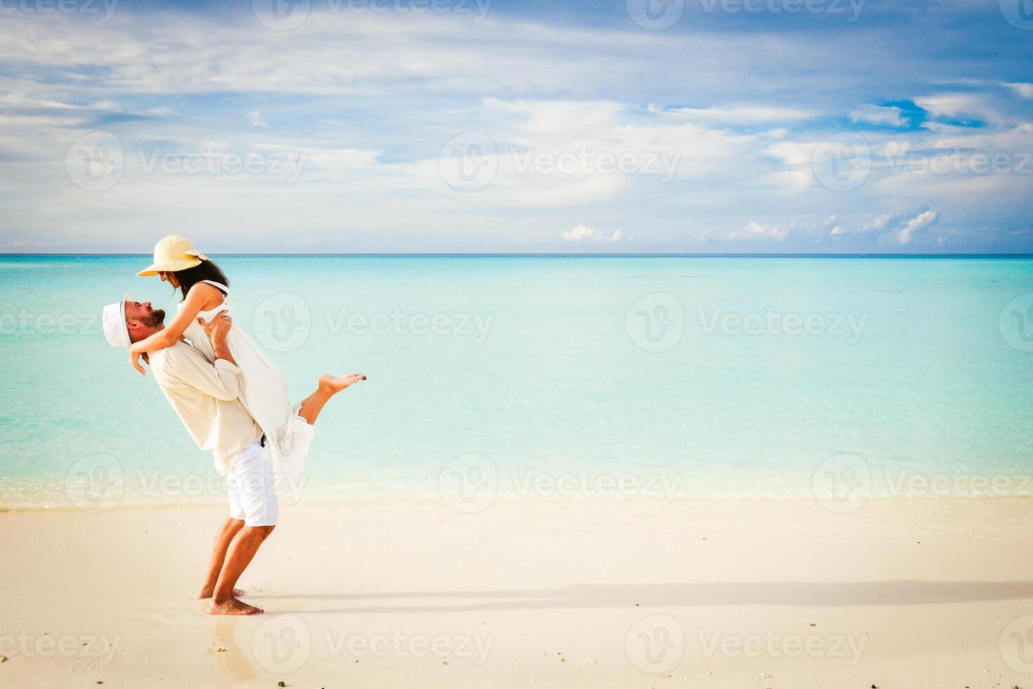 Young happy couple on white beach at summer vacation in Maldives. Fulidhoo island.Husband lifts wife share memories having fun on vacation honeymoon copy space background photo