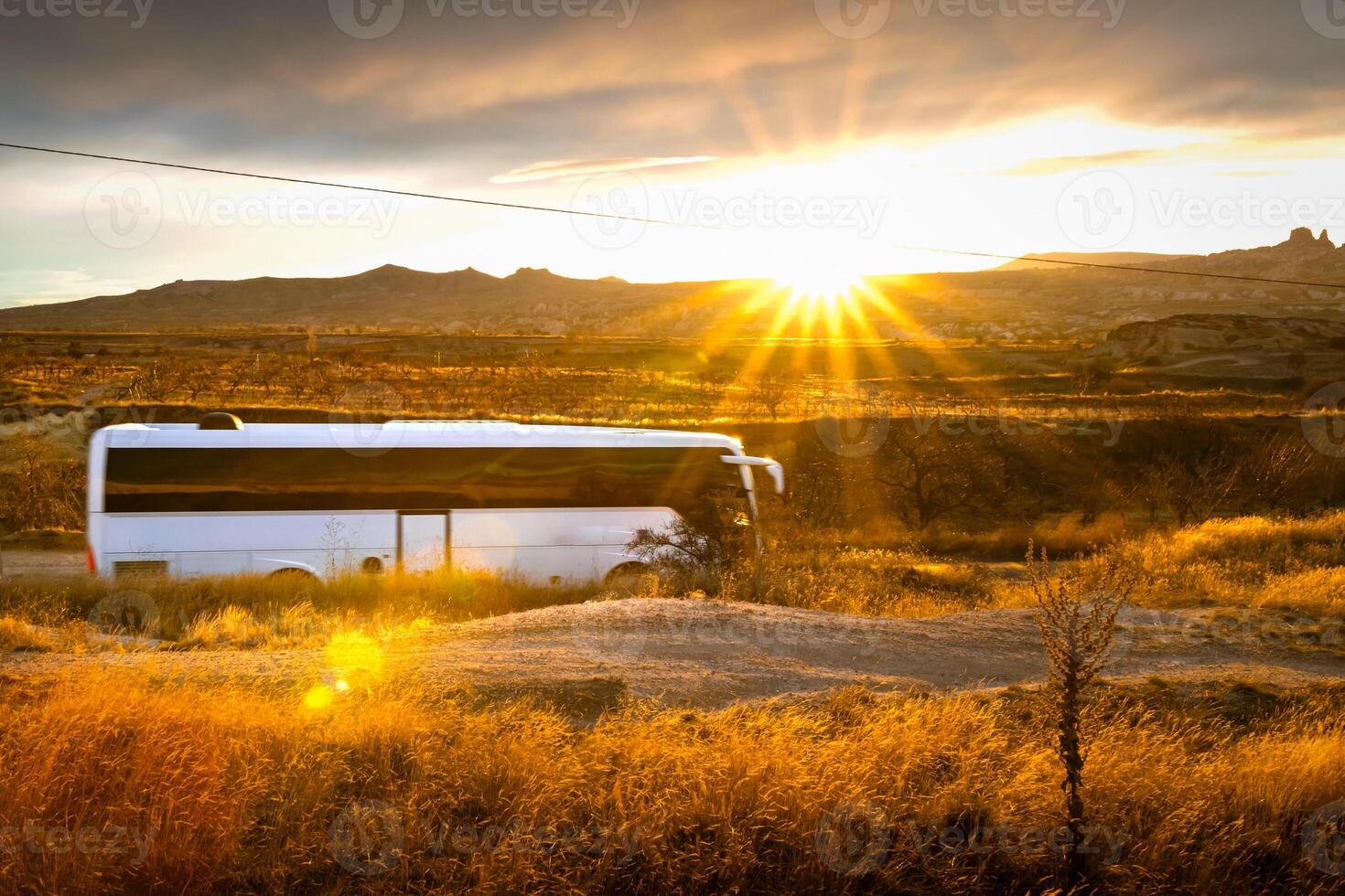 Fast white bus is passing rocky landscape of Cappadocia with sunset in the background. Travel trip excursion in europe destinations. TURKEY TRAVEL excursion concept background photo