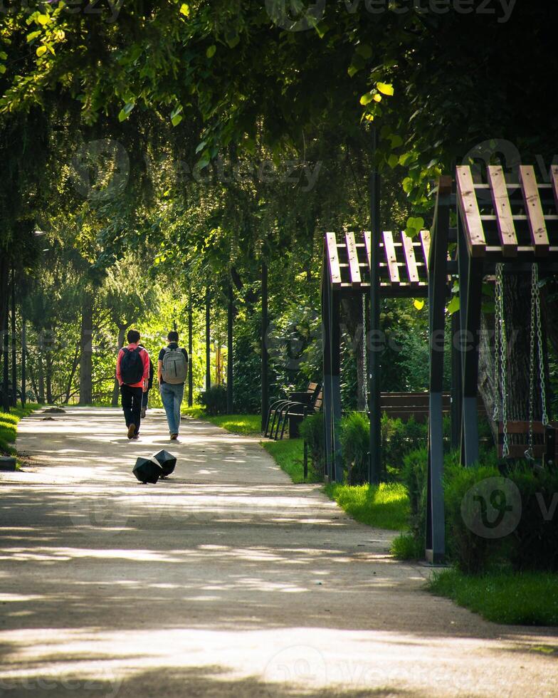 Tbilisi, Georgia - 1st june, 2024 young two friends students walk in new green park area with paths and benches in Saburtalo district, by medical university photo