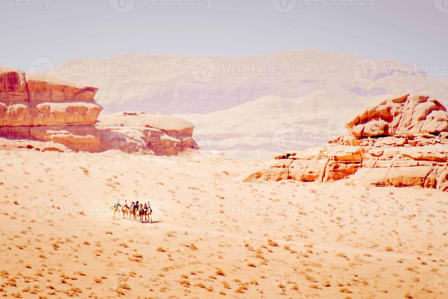 Group of tourist ride on camel caravan in wadi rum desert with scenic rock formations panorama photo