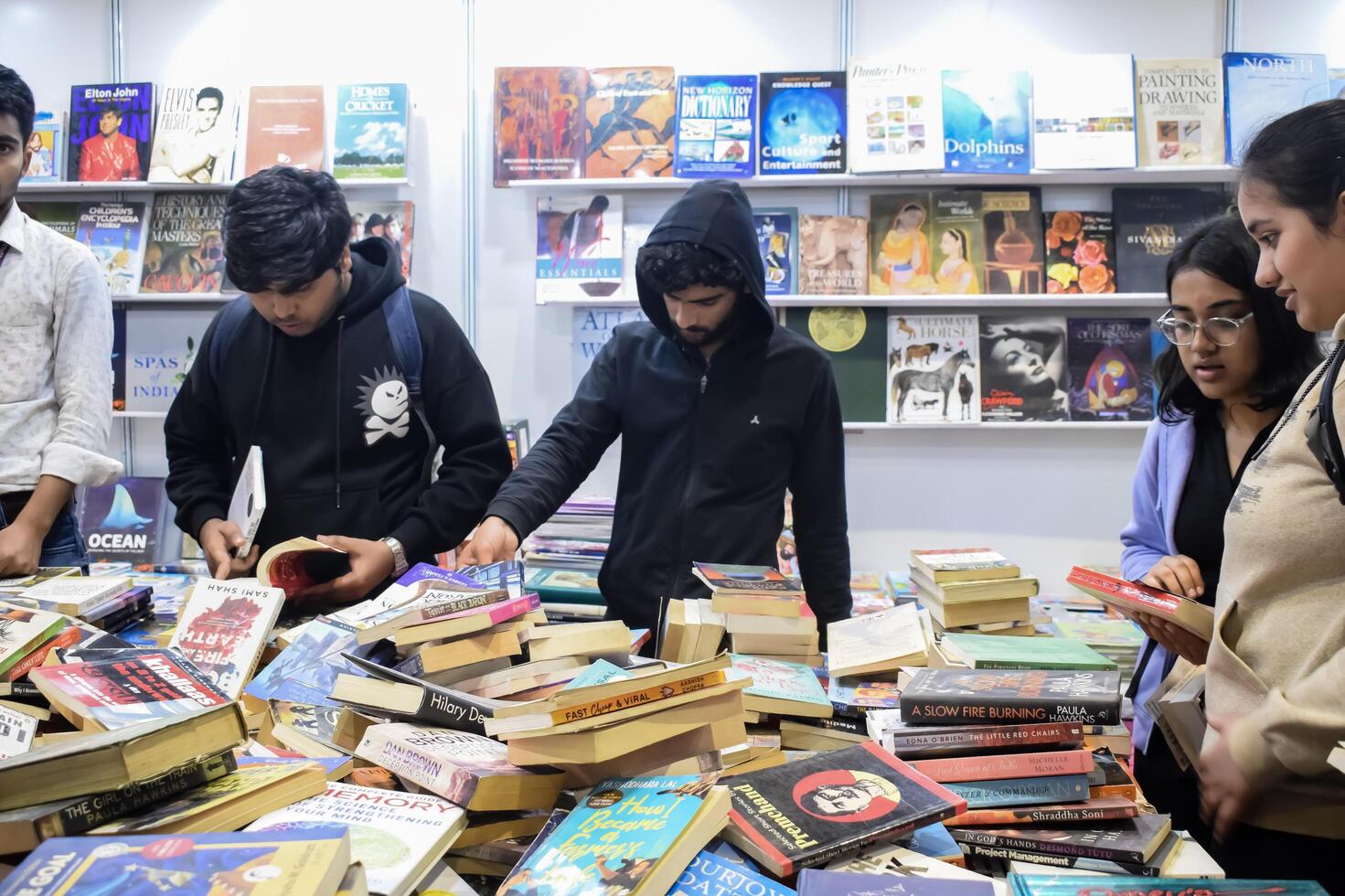 Delhi, India, June 7 2024 - Various age group people reading variety of Books on shelf inside a book-stall at Delhi International Book Fair, Books in Annual Book Fair at Bharat Mandapam complex photo