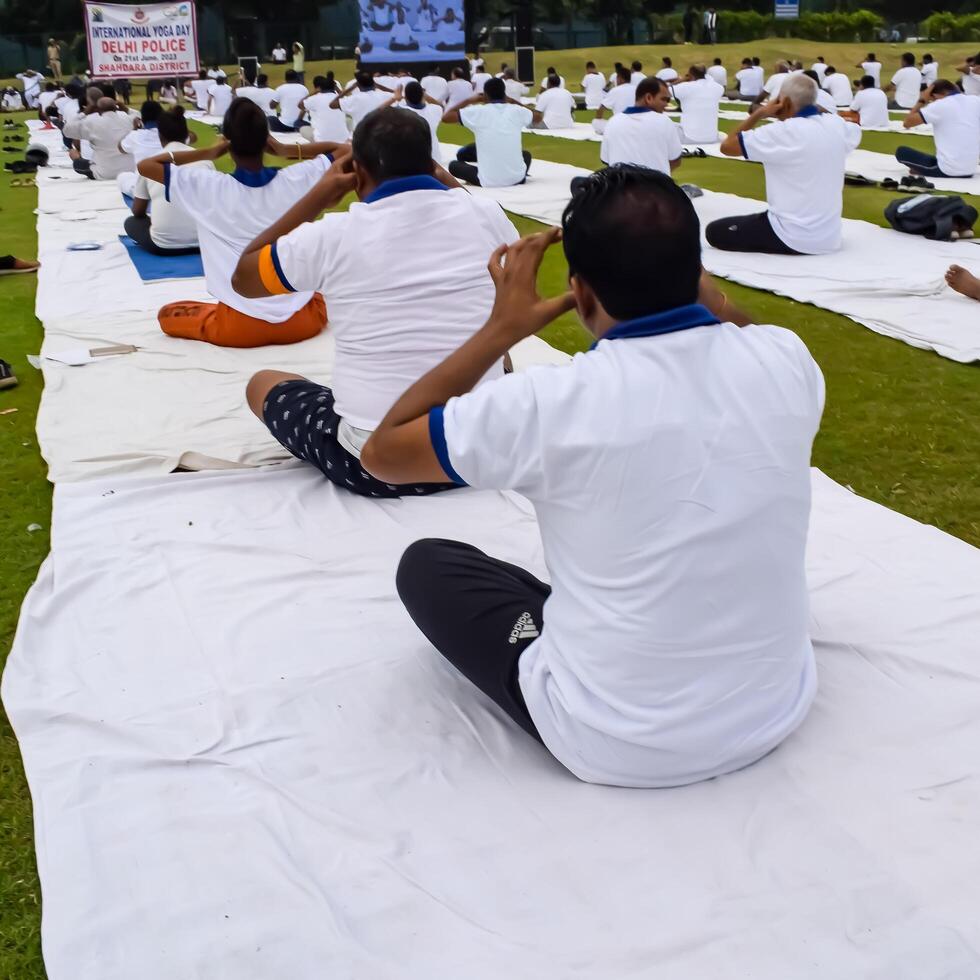 New Delhi, India, June 10, 2024 - Group Yoga exercise session for people at Yamuna Sports Complex in Delhi on International Yoga Day, Big group of adults attending yoga class in cricket stadium photo