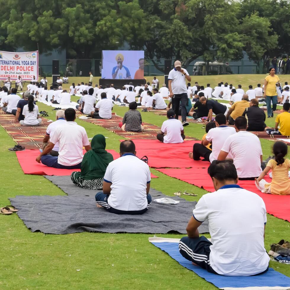 New Delhi, India, June 10, 2024 - Group Yoga exercise session for people at Yamuna Sports Complex in Delhi on International Yoga Day, Big group of adults attending yoga class in cricket stadium photo