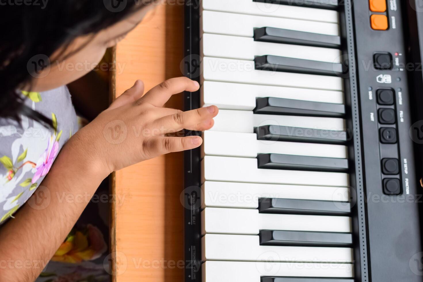 Asian cute girl playing the synthesizer or piano. Cute little kid learning how to play piano. Child's hands on the keyboard indoor. photo