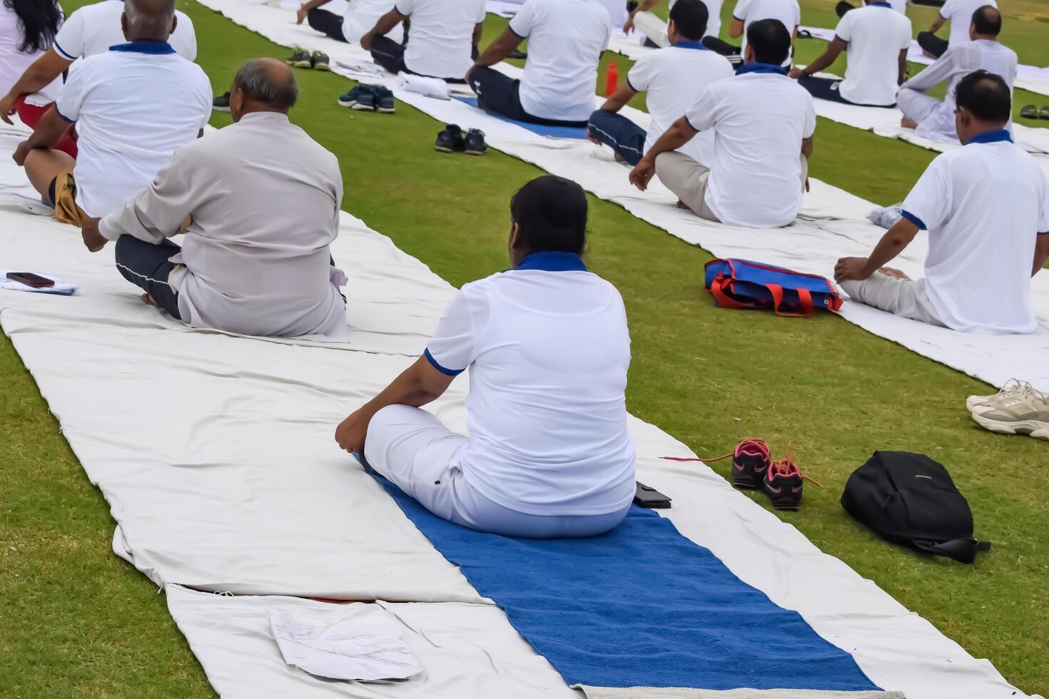 New Delhi, India, June 10, 2024 - Group Yoga exercise session for people at Yamuna Sports Complex in Delhi on International Yoga Day, Big group of adults attending yoga class in cricket stadium photo