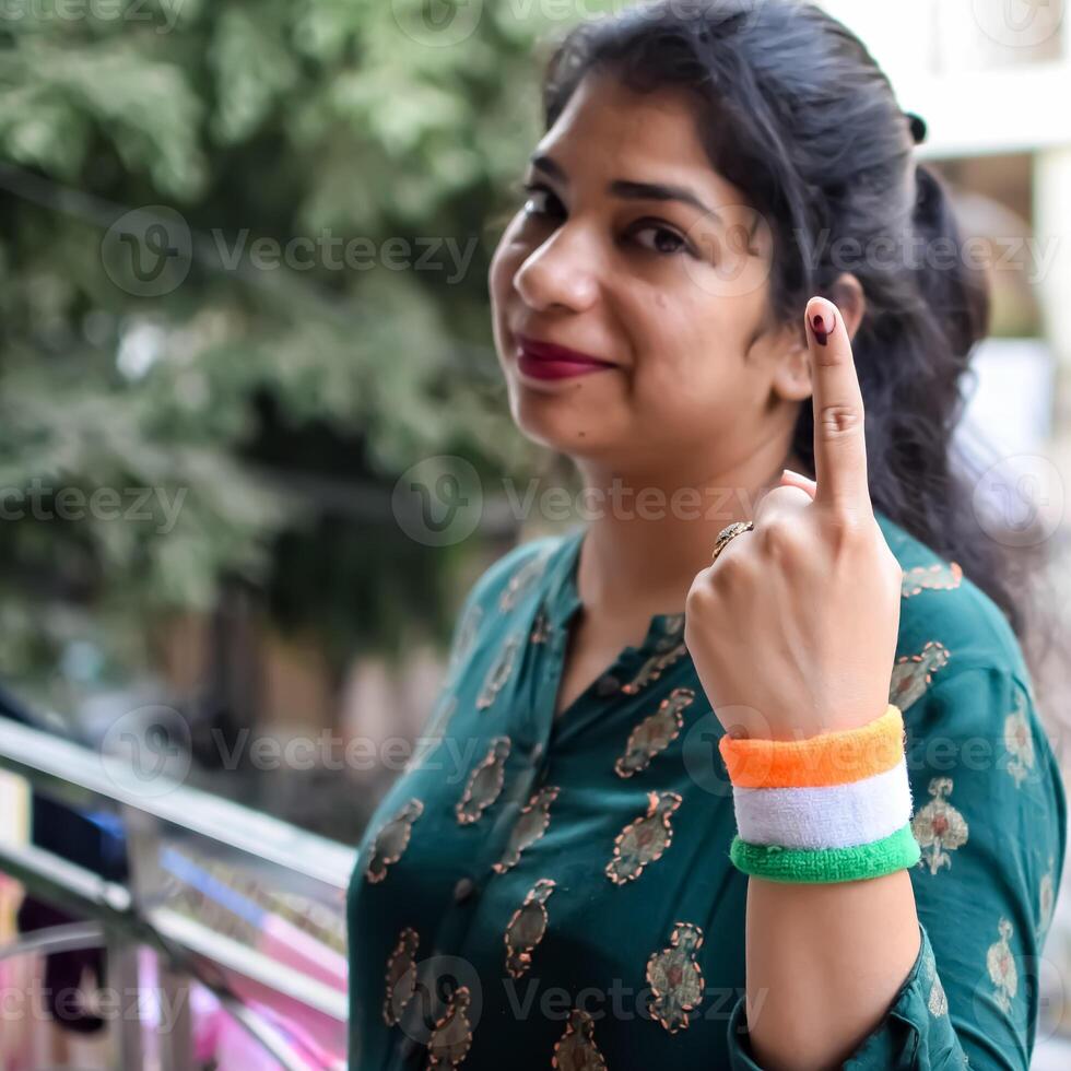 Smart young lady showing her ink-marked fingers after casting votes in front of polling booth of east Delhi area for general Lok Sabha Elections 2024 photo