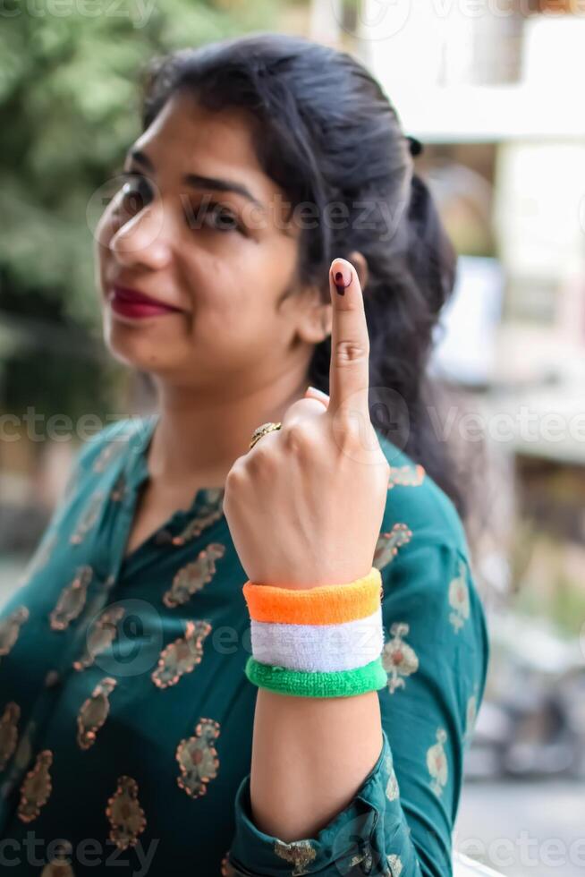 Smart young lady showing her ink-marked fingers after casting votes in front of polling booth of east Delhi area for general Lok Sabha Elections 2024 photo
