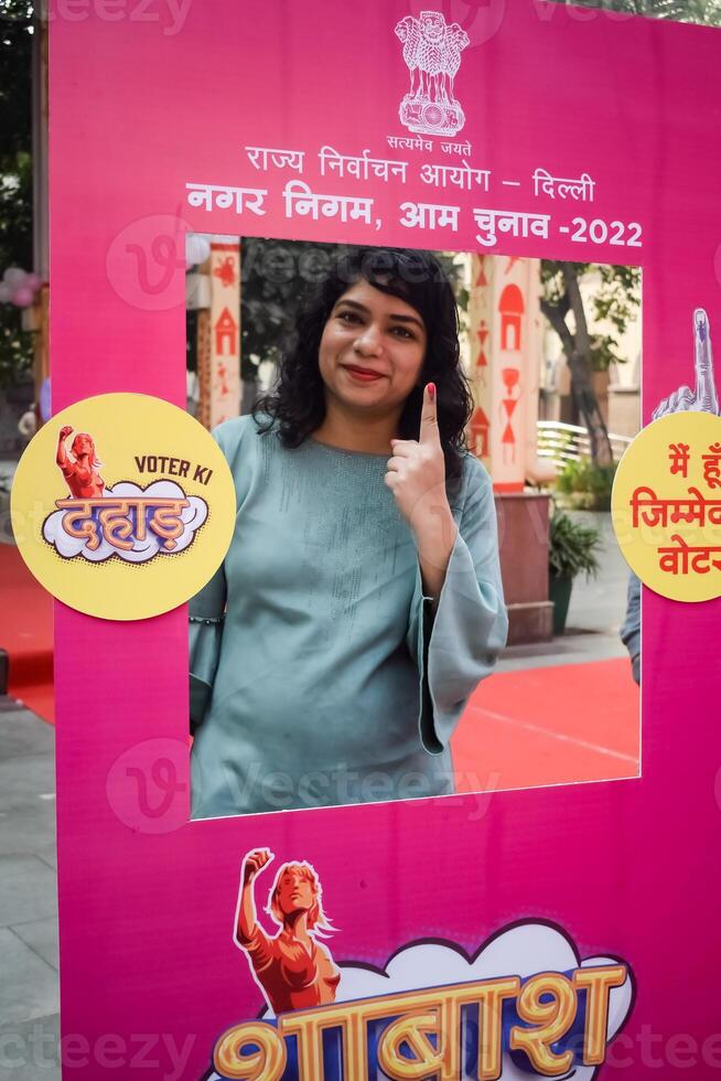 Smart young lady showing her ink-marked fingers after casting votes in front of polling booth of east Delhi area for general Lok Sabha Elections 2024 photo