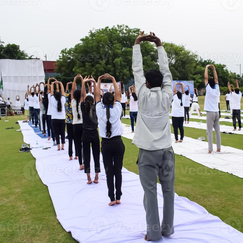 Group Yoga exercise session for people of different age groups at cricket stadium in Delhi on International Yoga Day, Big group of adults attending yoga session photo