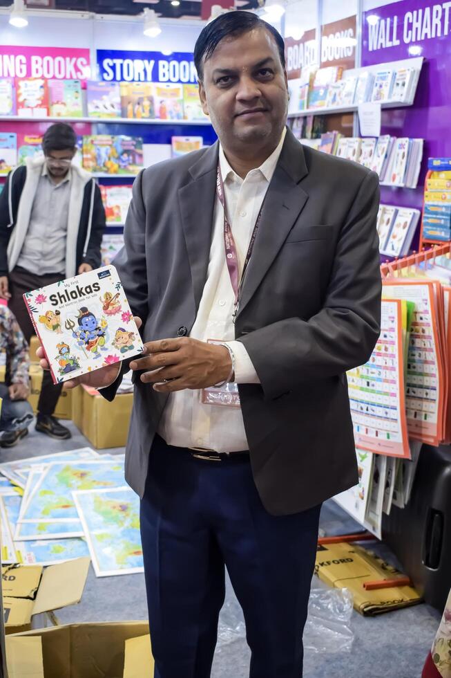 Delhi, India, May 17 2024 - Various age group people reading variety of Books on shelf inside a book-stall at Delhi International Book Fair, Books in Annual Book Fair at Bharat Mandapam complex photo
