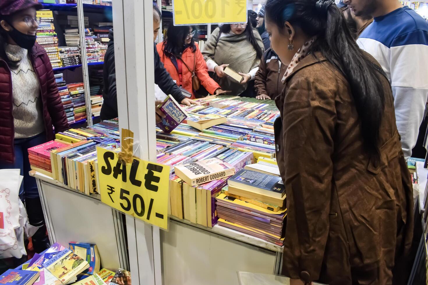 Delhi, India, May 17 2024 - Various age group people reading variety of Books on shelf inside a book-stall at Delhi International Book Fair, Books in Annual Book Fair at Bharat Mandapam complex photo
