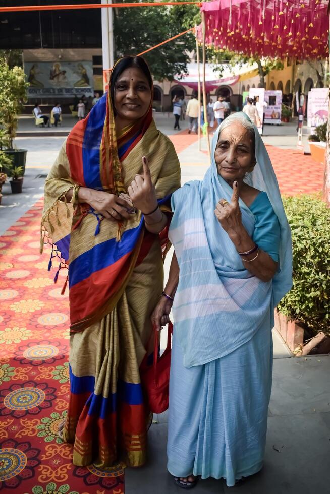 New Delhi, India - May 25 2024 - Unidentified people showing their ink-marked fingers after casting votes in front of polling booth of east Delhi area for general Lok Sabha Elections 2024 photo