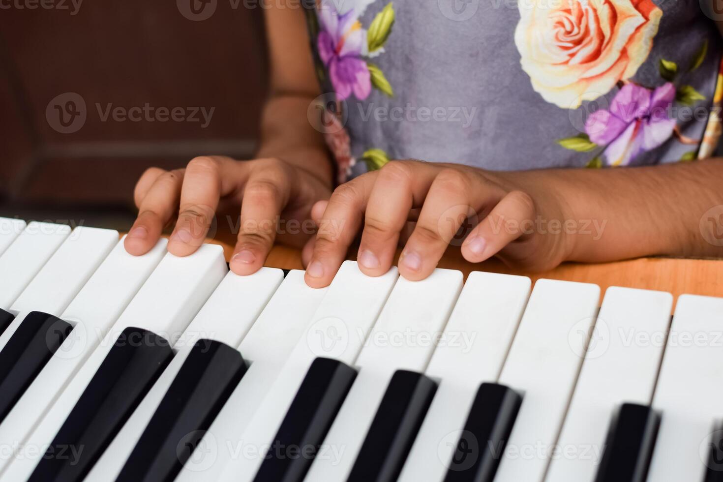 Asian cute girl playing the synthesizer or piano. Cute little kid learning how to play piano. Child's hands on the keyboard indoor. photo