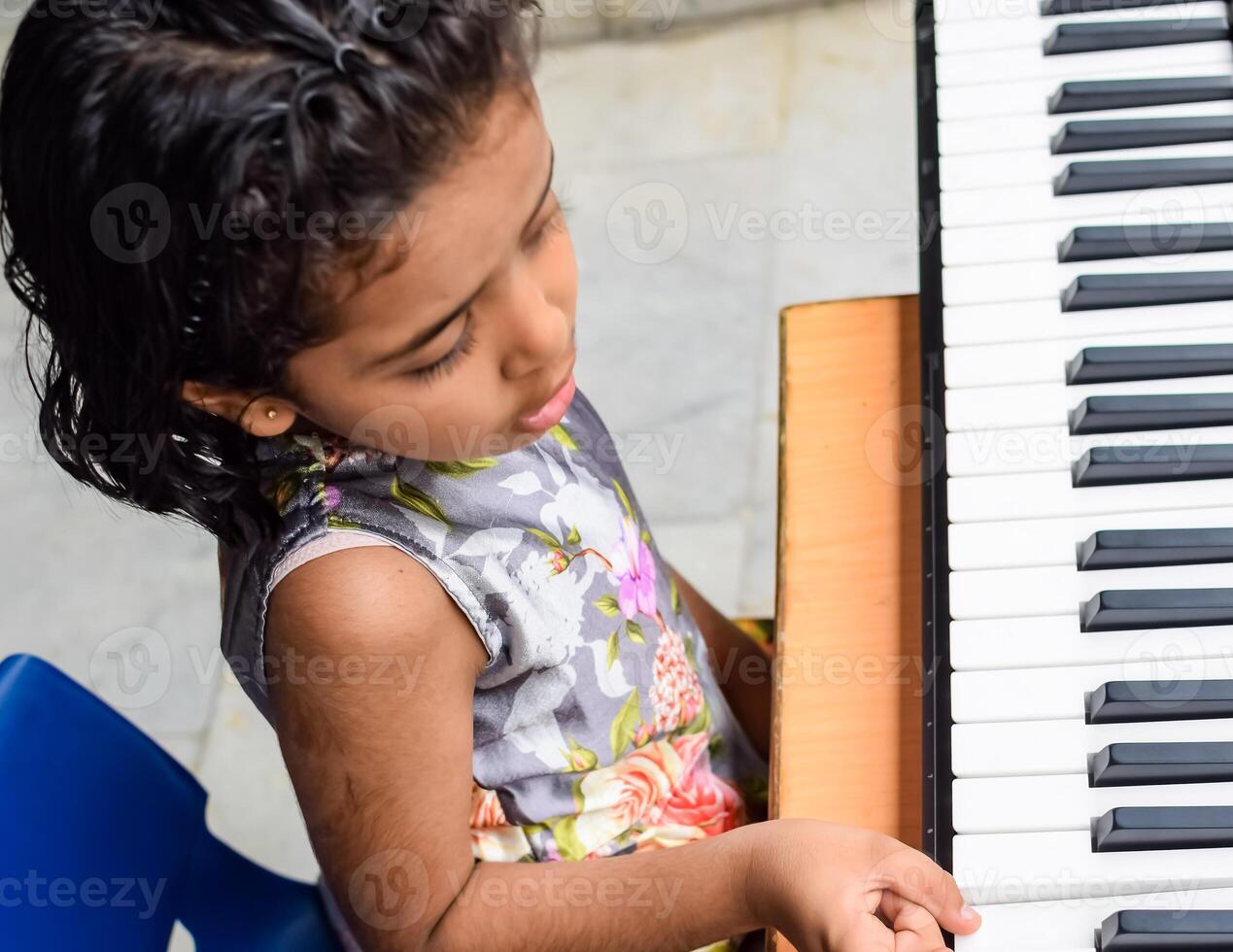 Asian cute girl playing the synthesizer or piano. Cute little kid learning how to play piano. Child's hands on the keyboard indoor. photo