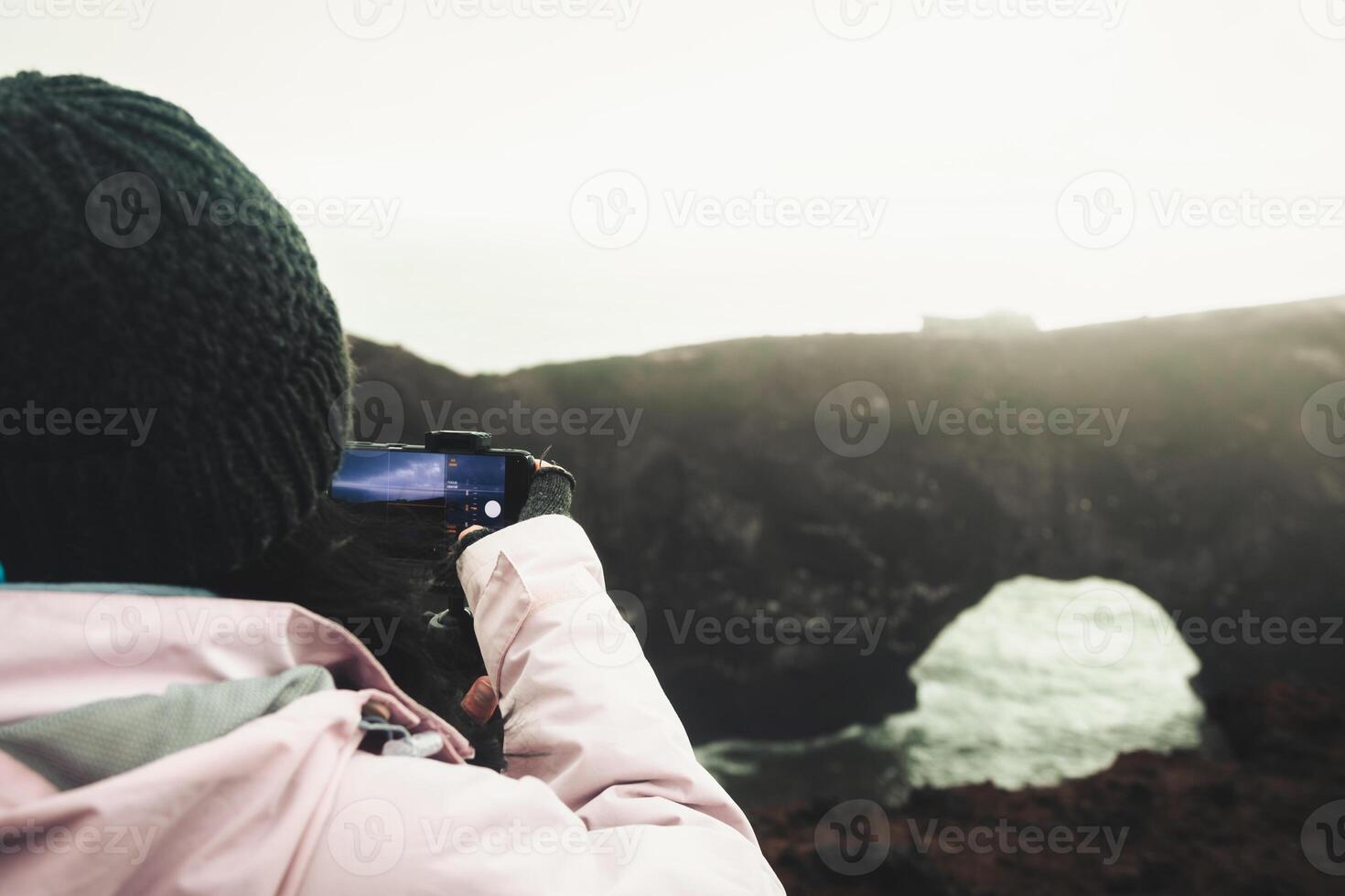 Woman tourist visit sightseeing Dyrholaey landmark hold smart phone photograph capture natural wonders in Iceland to post on social media. Copy space background panorama photo