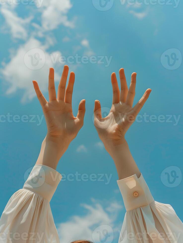 Two hands are raised in the air, reaching towards the sky photo