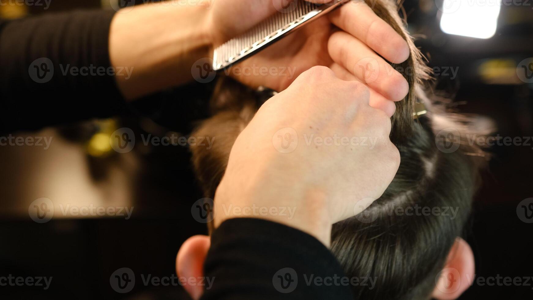Closeup View Of barber using hair clip to fix the hair for cut and styling it. Hairdresser use pinsn hair salon. service in a modern barbershop in a dark key lightning with warm light back view photo
