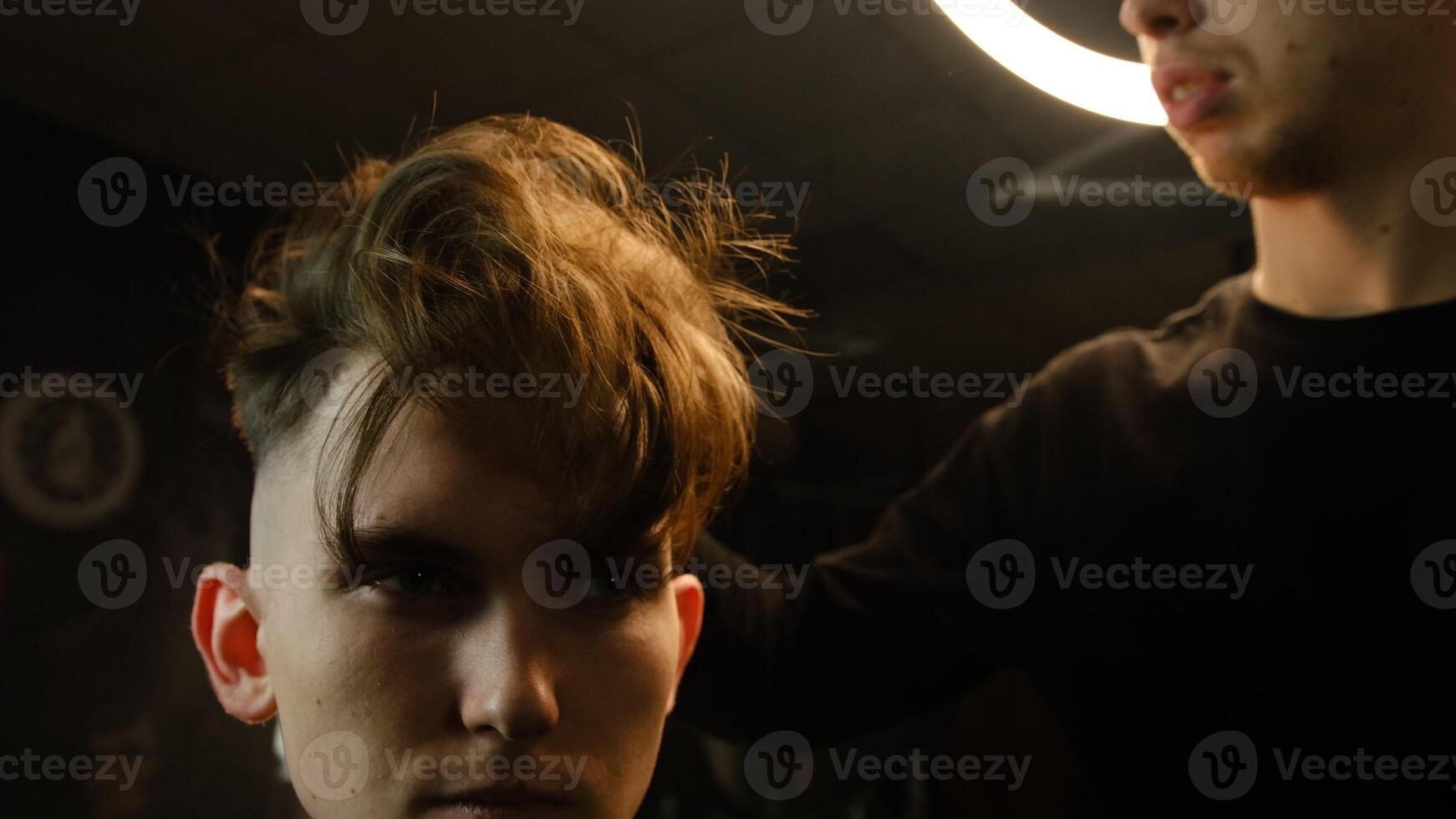 Barber shop. Man in barber's chair, hairdresser shaking hairs by the hand before cut and styling it. Concept Barbershop. front view in dark key lightning with warm light photo