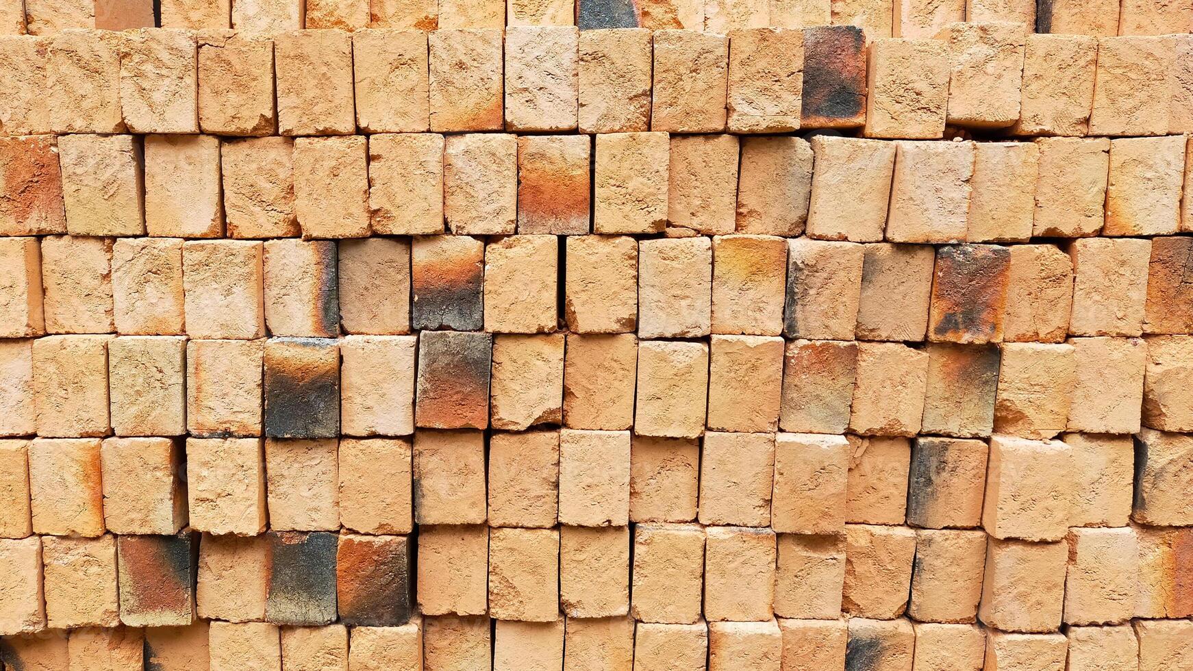 Stack of neatly arranged red clay bricks with natural texture and varied colors in a construction site background showcasing the building materials for architectural and construction projects photo