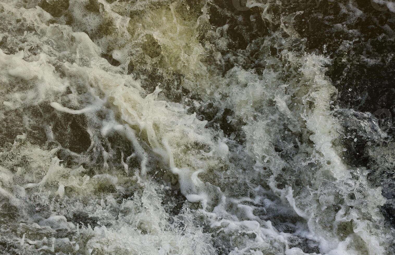 Waves of water of the river and the sea meet each other during high tide and low tide. Deep blue stormy sea water surface with white foam and waves pattern, background photo