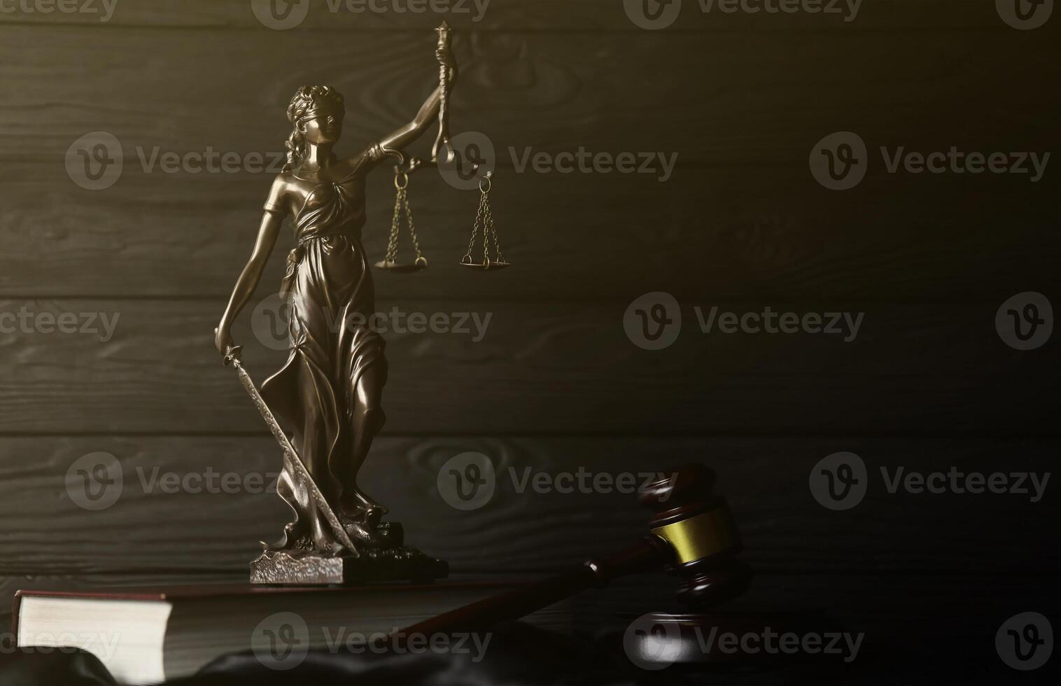 The Statue of Justice - lady justice or justitia the Roman goddess of Justice. Statue on brown book with judge gavel. Concept of judicial trial, courtroom process and lawyers work photo