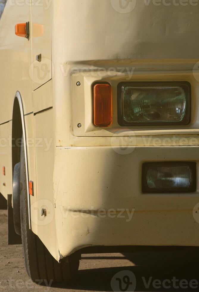 Photo of the hull of a large and long yellow bus. Close-up front view of a passenger vehicle for transportation and tourism