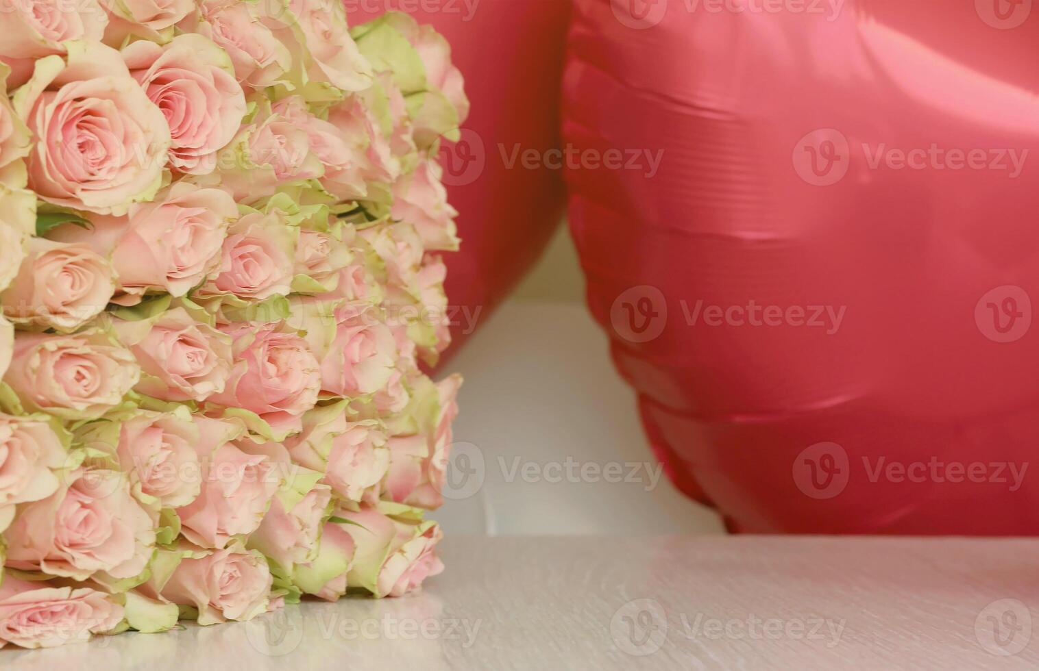 Bouquet of colorful roses and red balloons in shape of heart. Pink flowers full frame photo