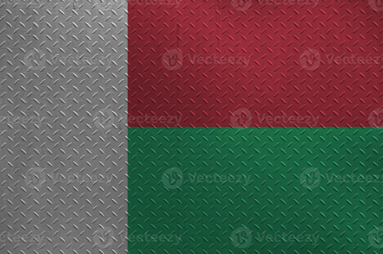 Madagascar flag depicted in paint colors on old brushed metal plate or wall closeup. Textured banner on rough background photo