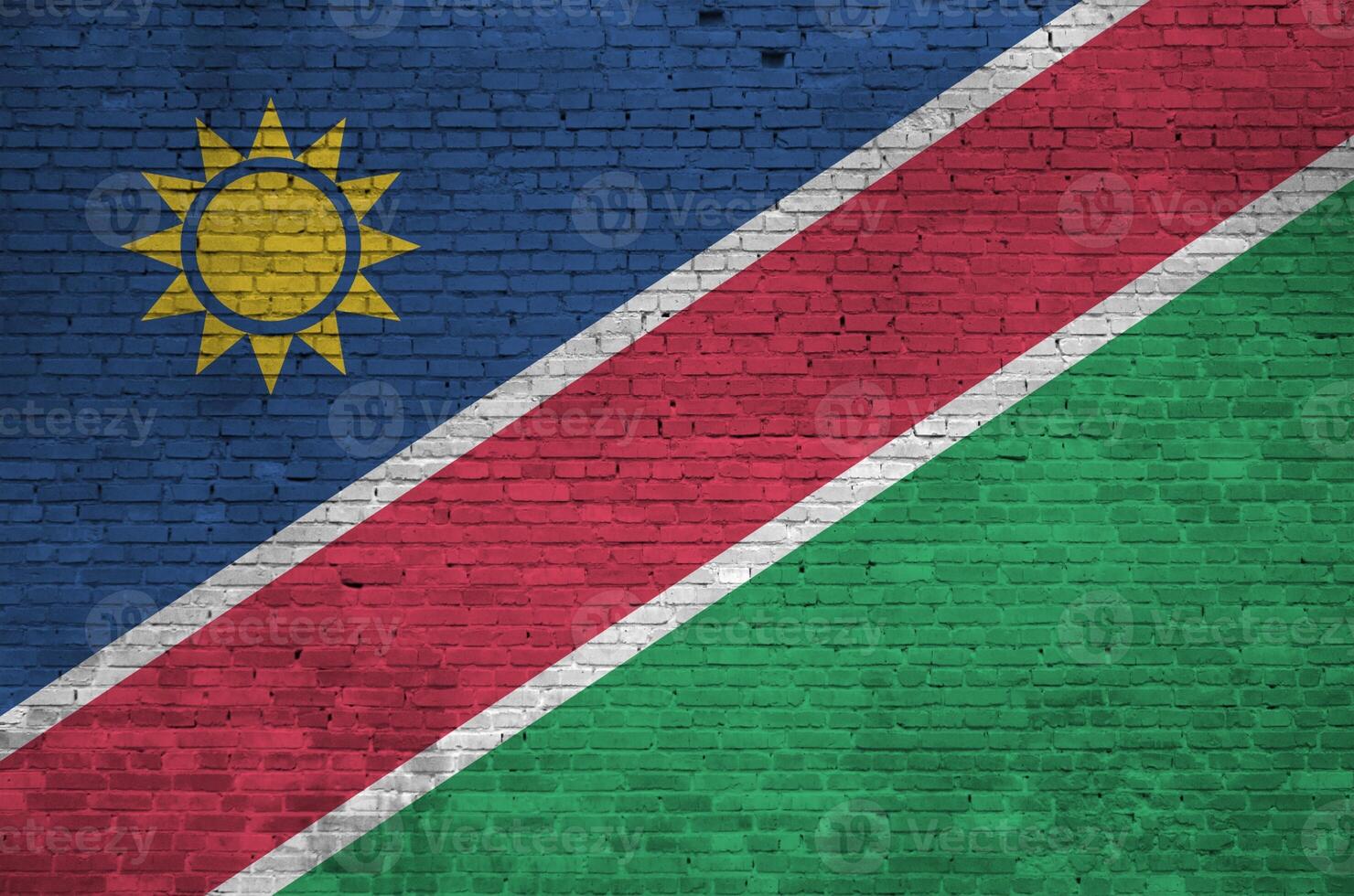 Namibia flag depicted in paint colors on old brick wall. Textured banner on big brick wall masonry background photo