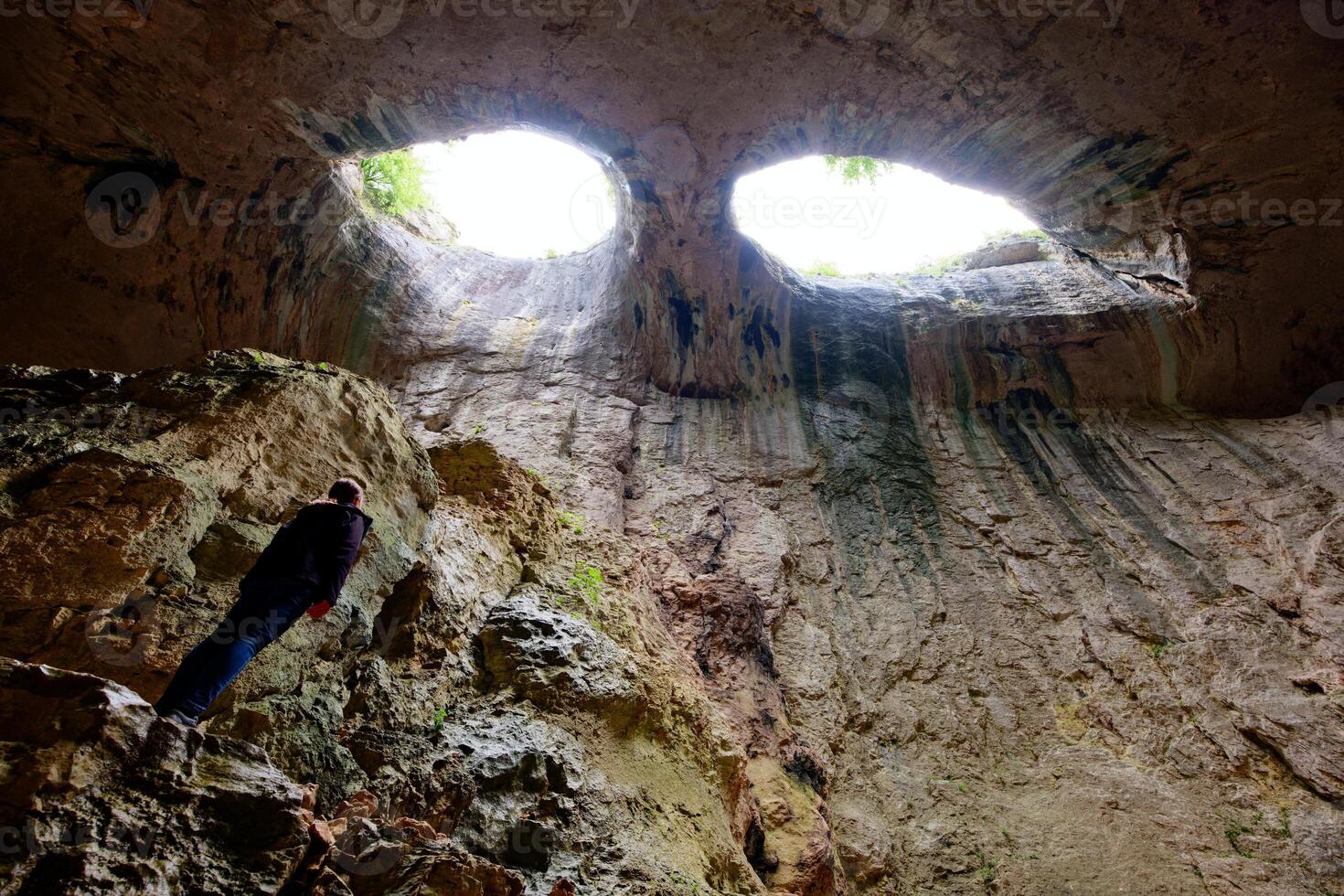 A person looking up in the Prohodna Cave also known as The Eyes of God in Bulgaria. photo