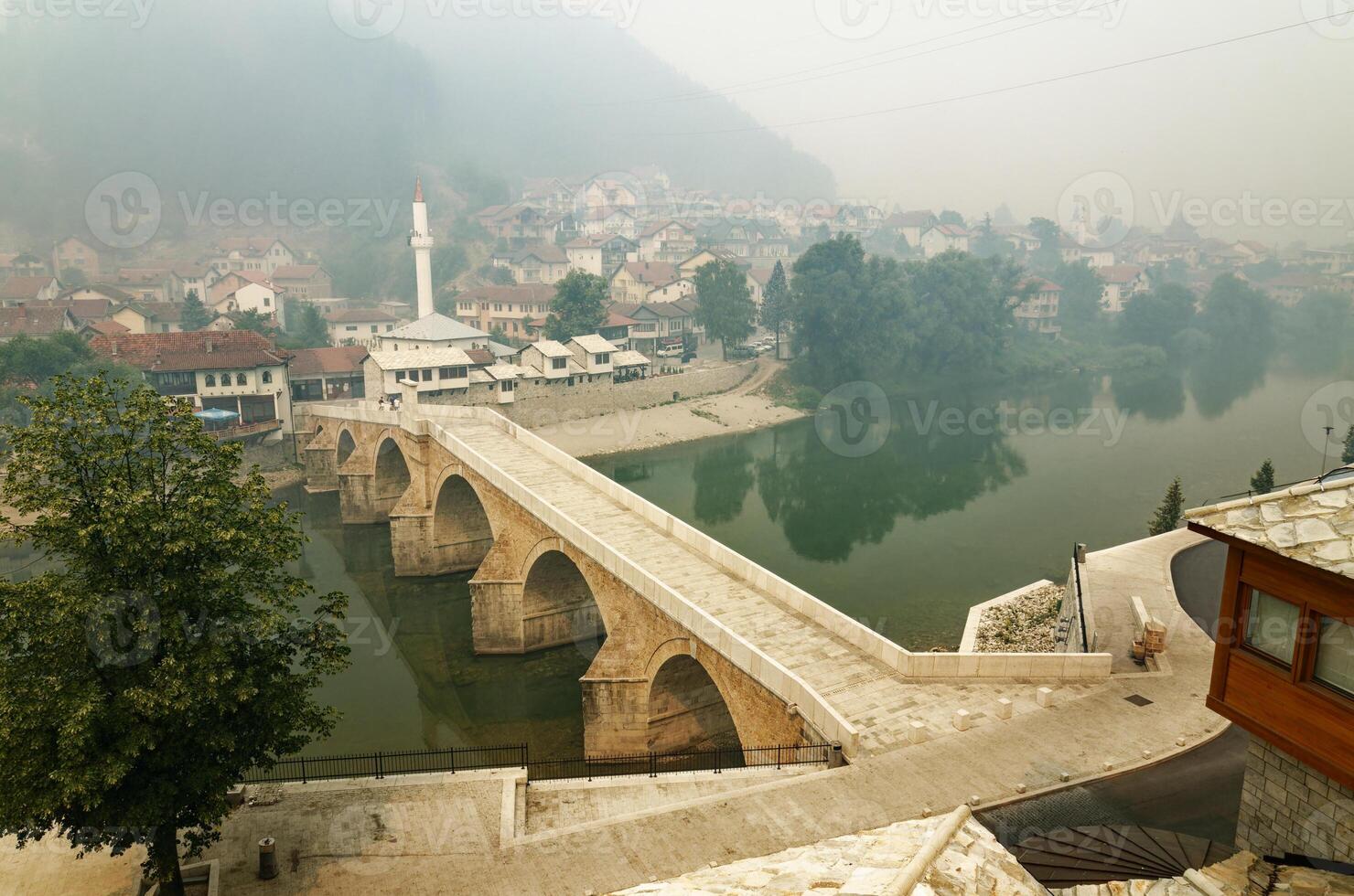 Old stone bridge of Konjic in Bosnia and Herzegovina during a foggy day. Symbol of the city. Neretva river running below the bridge. photo