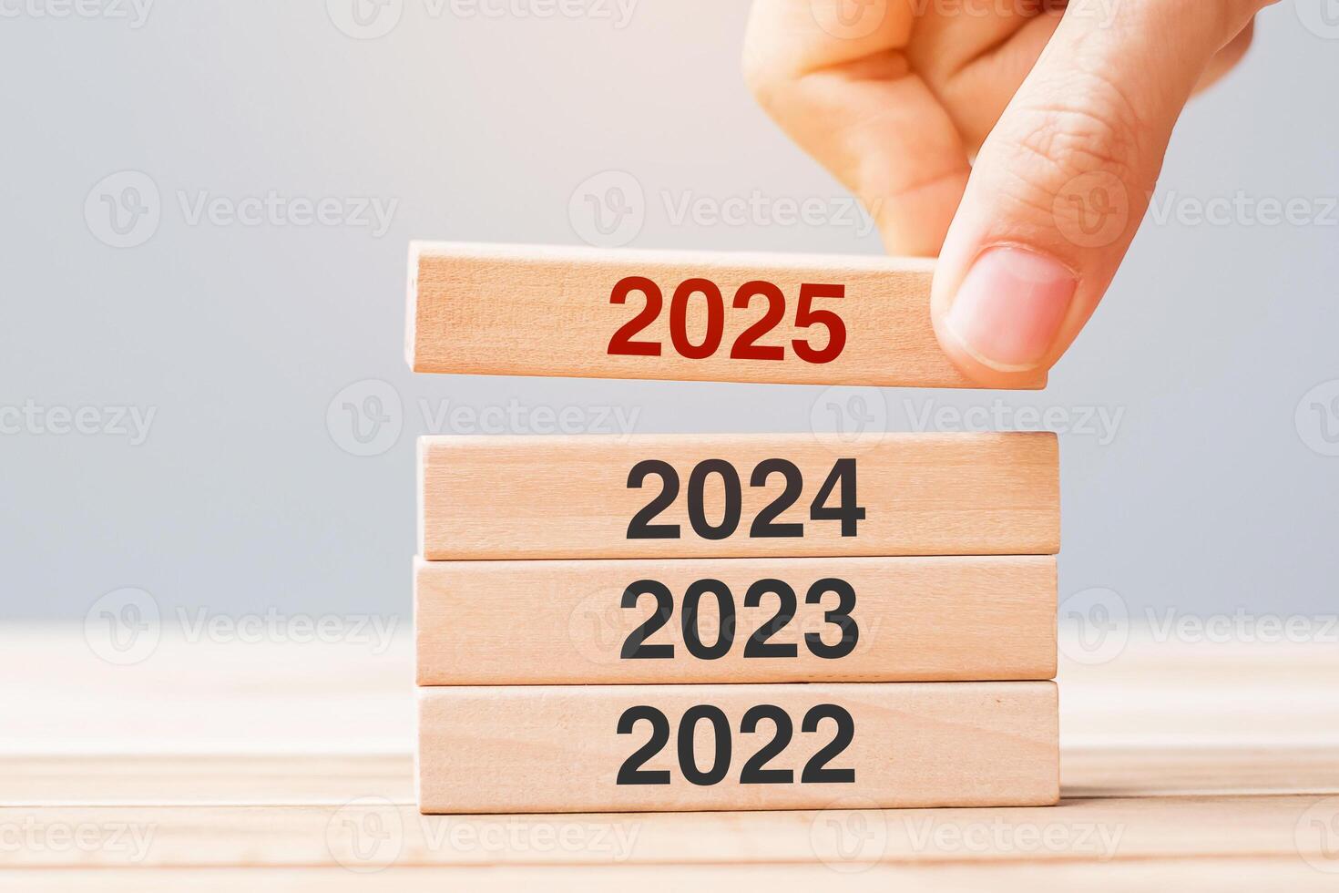 2025 block over 2024 and 2023 wooden building on table background. Business planning, Risk Management, Resolution, strategy, solution, goal, New Year New You and happy holiday concepts photo