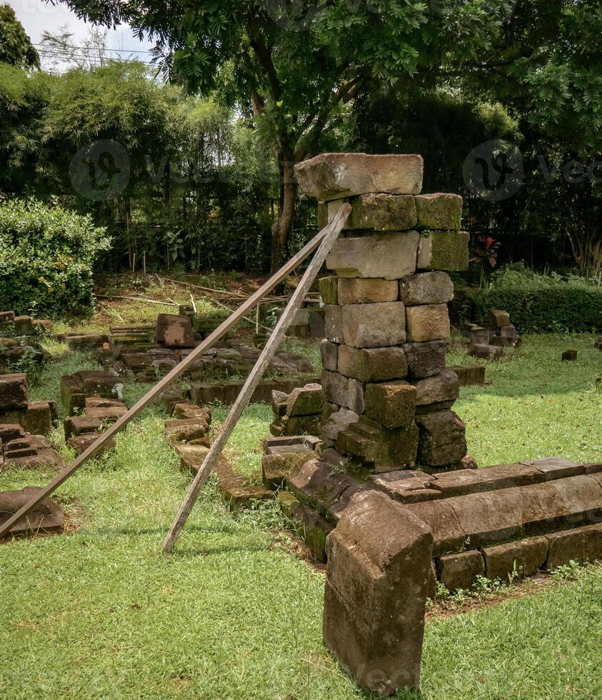 piles of ancient temple stones arranged and supported by wood as a restoration experiment photo