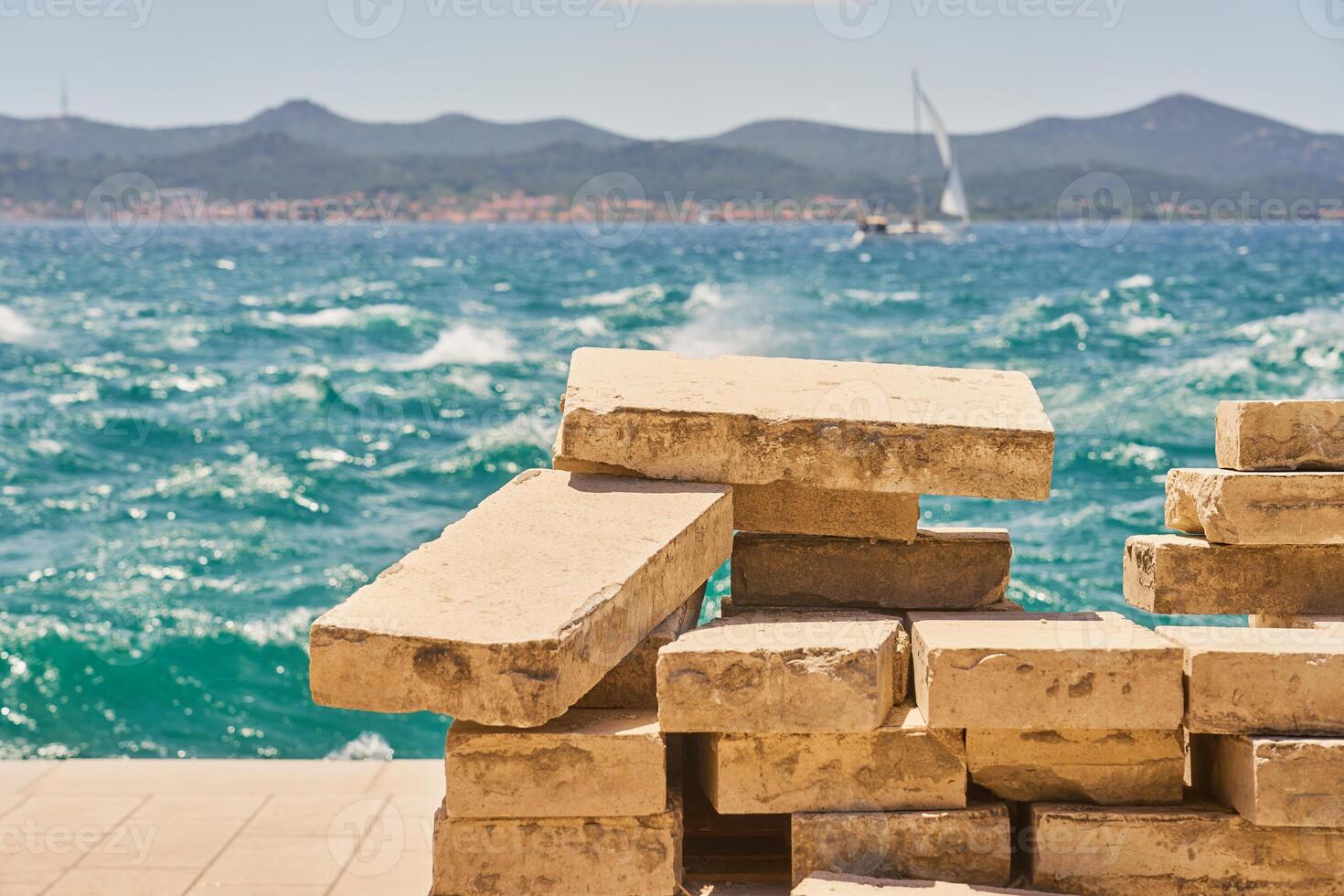 Old granite tiles for laying a sidewalk with the sea in the background. photo