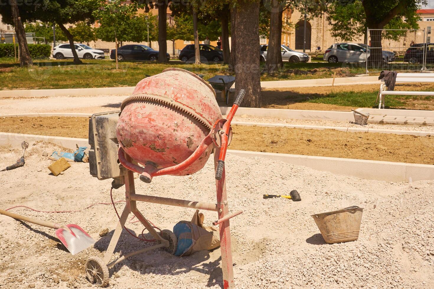 Concrete mixer in the sun with a park in the background. photo