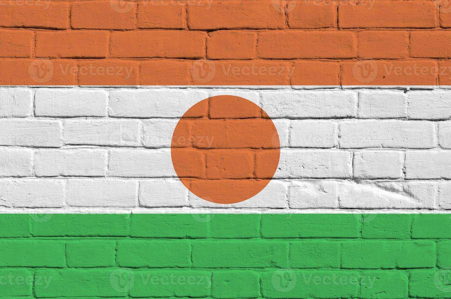 Niger flag depicted in paint colors on old brick wall. Textured banner on big brick wall masonry background photo