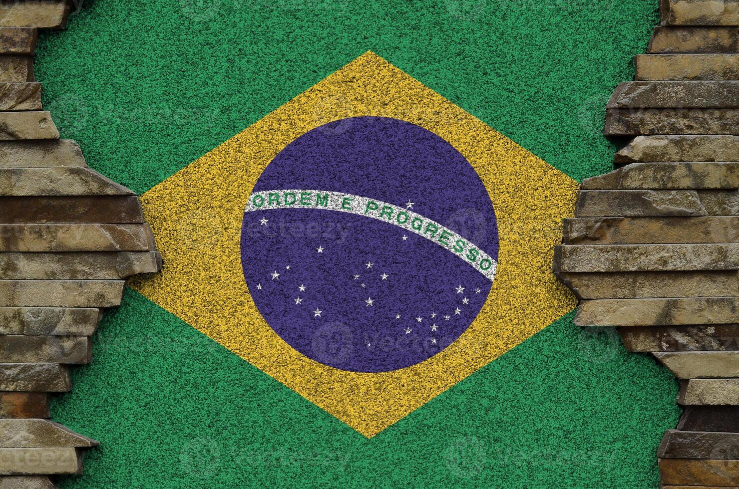 Brazil flag depicted in paint colors on old stone wall closeup. Textured banner on rock wall background photo