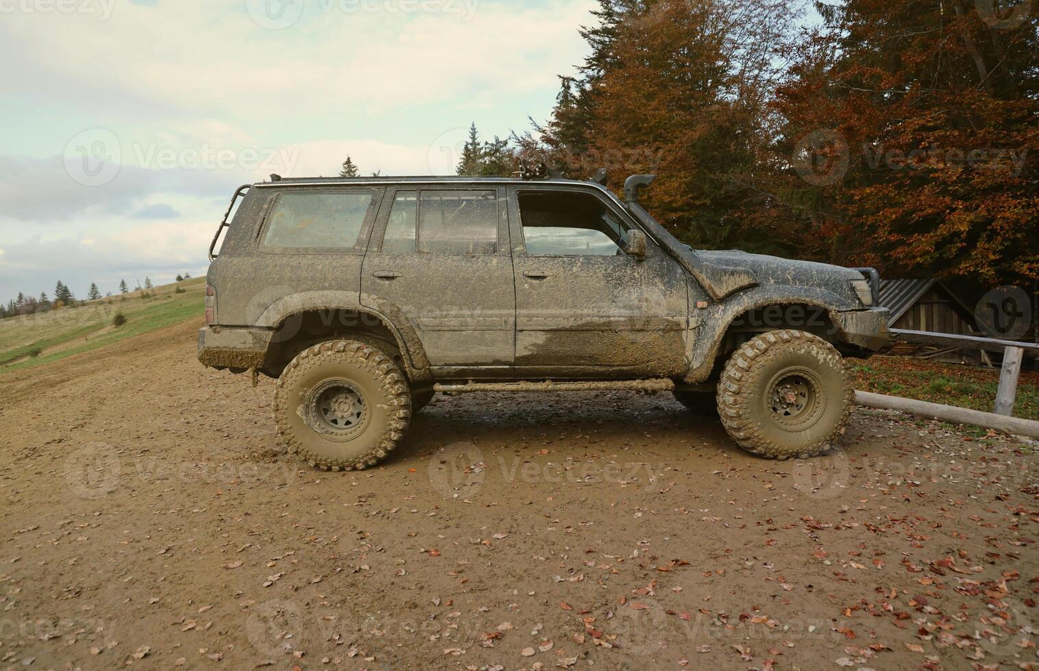 Automobile in a countryside landscape with a mud road. Off-road 4x4 suv automobile with ditry body after drive in muddy road photo