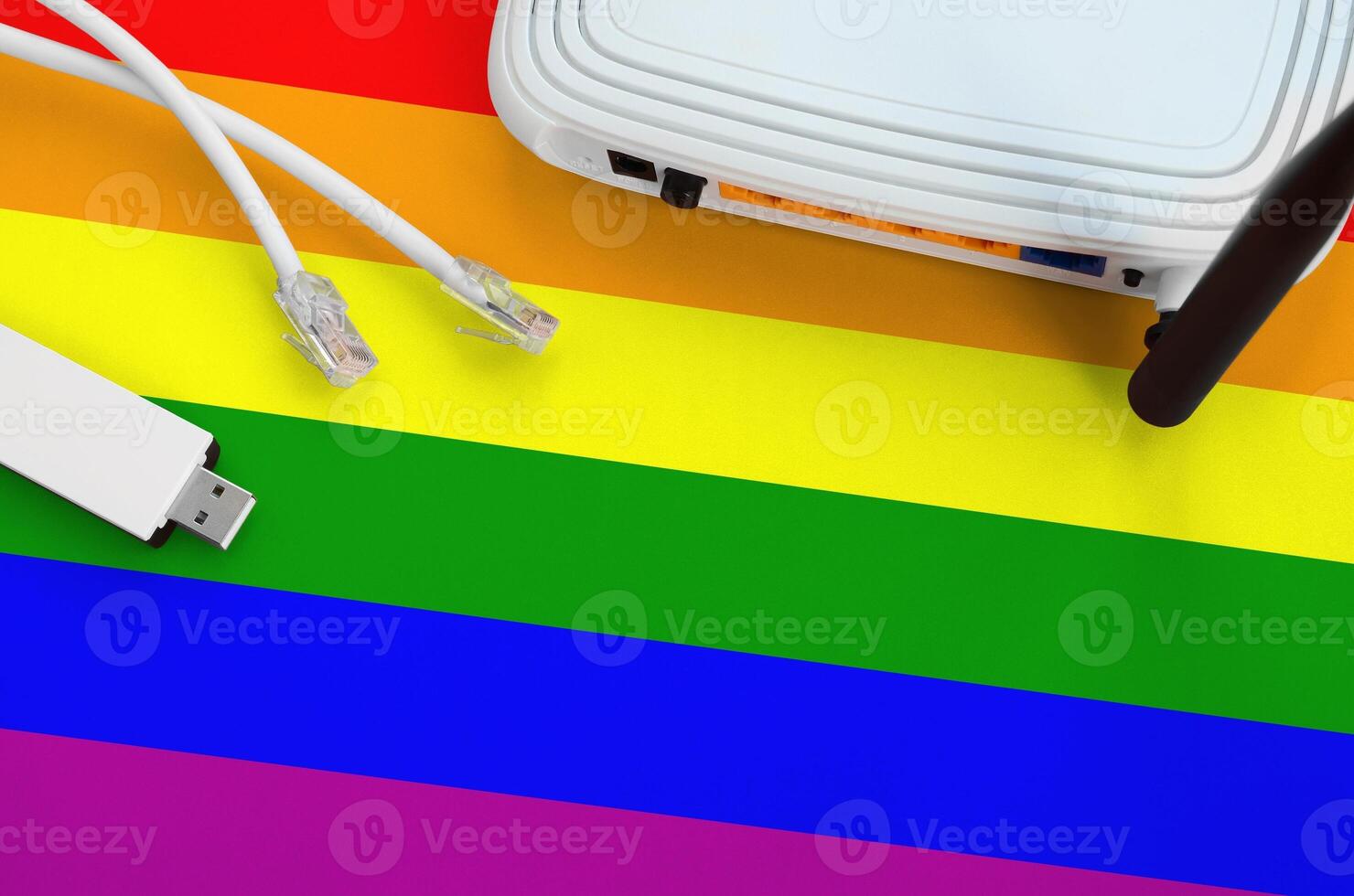 LGBT community flag depicted on table with internet rj45 cable, wireless usb wifi adapter and router. Internet connection concept photo
