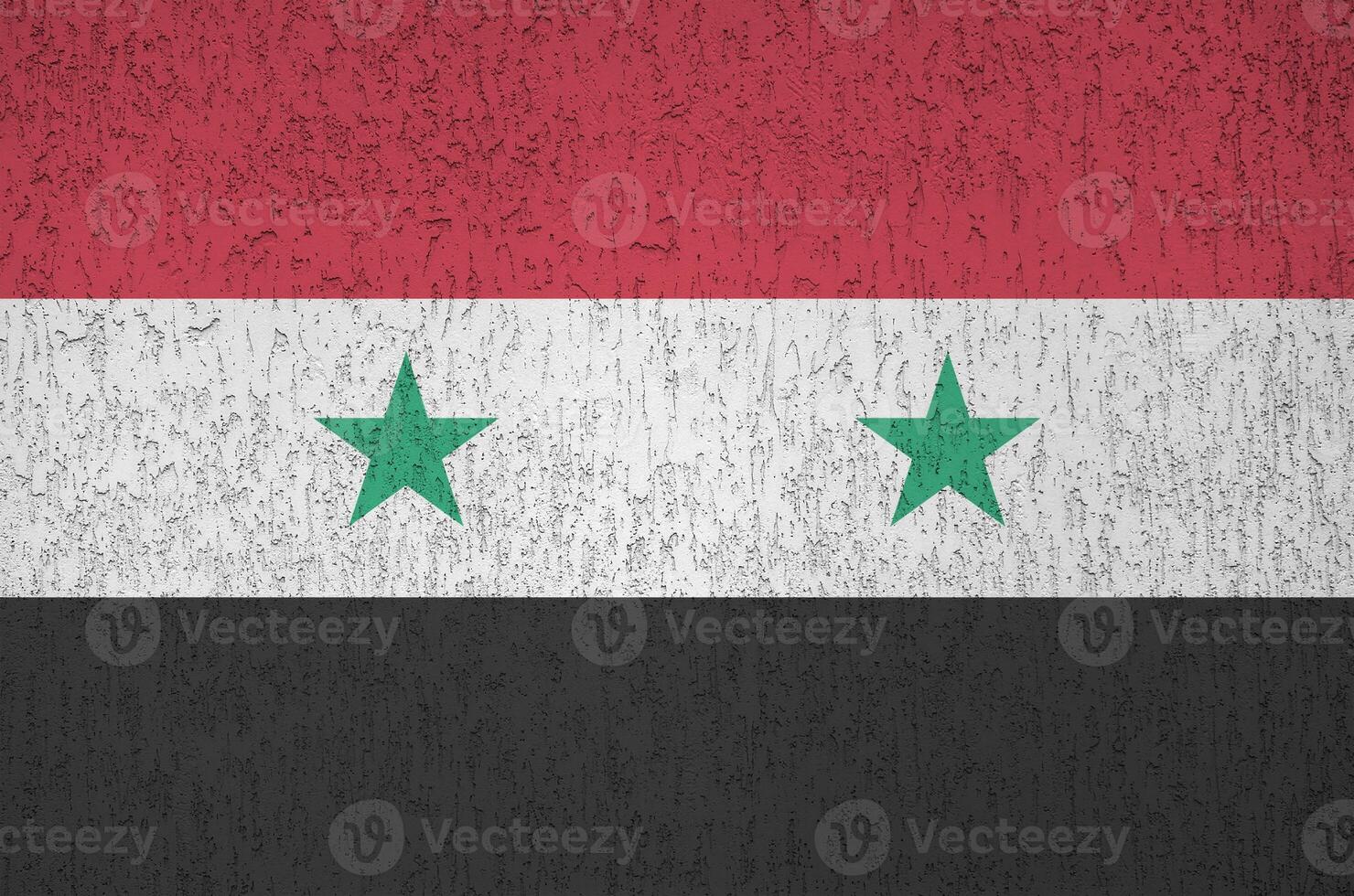 Syria flag depicted in bright paint colors on old relief plastering wall. Textured banner on rough background photo