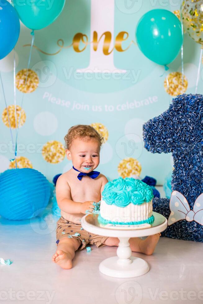 Baby boy playing with a cake during cake smash birthday party photo