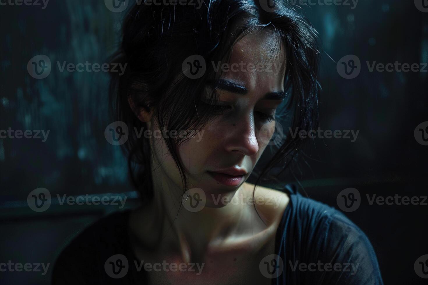 Intensely emotional portrait of a woman in despair, her face partly obscured by shadows, capturing a moment of profound sadness and vulnerability in a dark, atmospheric setting. photo