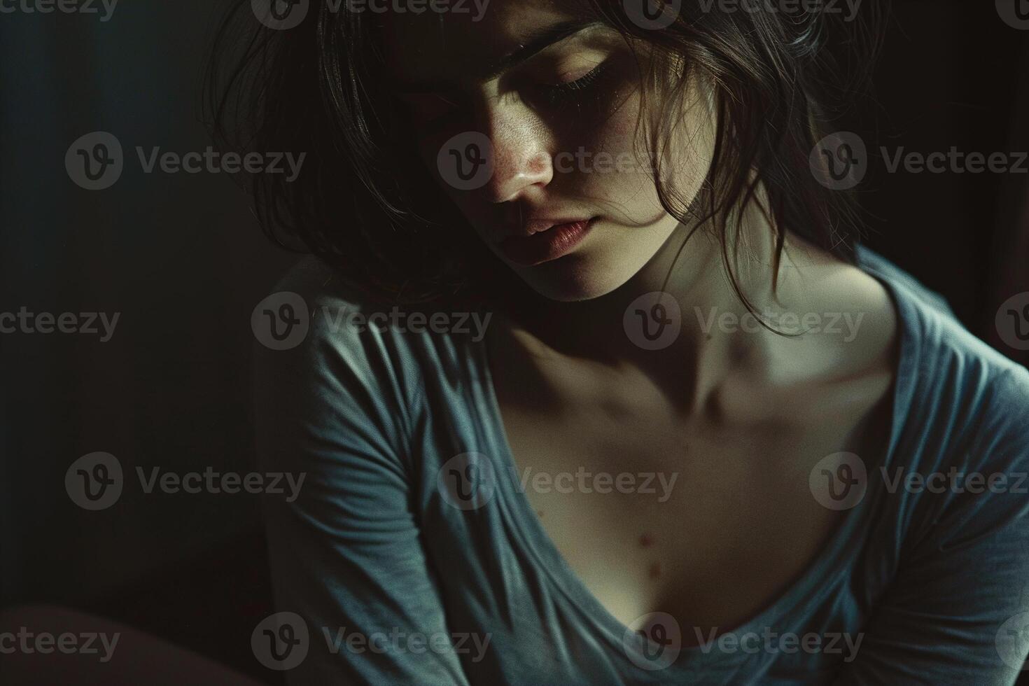 Intensely emotional portrait of a woman in despair, her face partly obscured by shadows, capturing a moment of profound sadness and vulnerability in a dark, atmospheric setting. photo