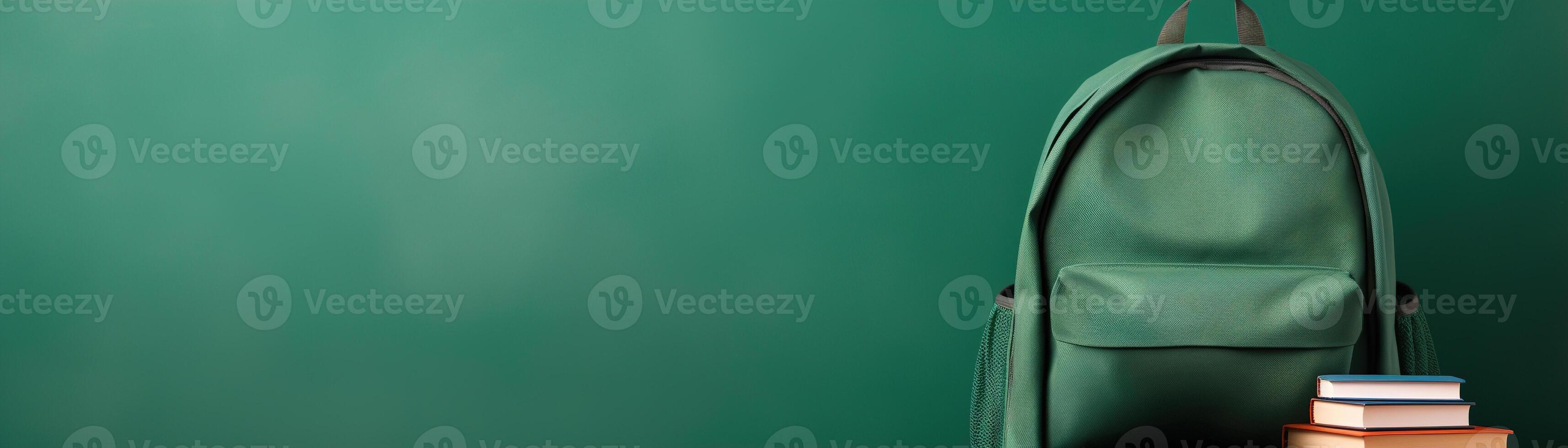 A stylish tan backpack and a stack of books against a green background, with ample space for text, ideal for educational themes and back-to-school campaigns. photo