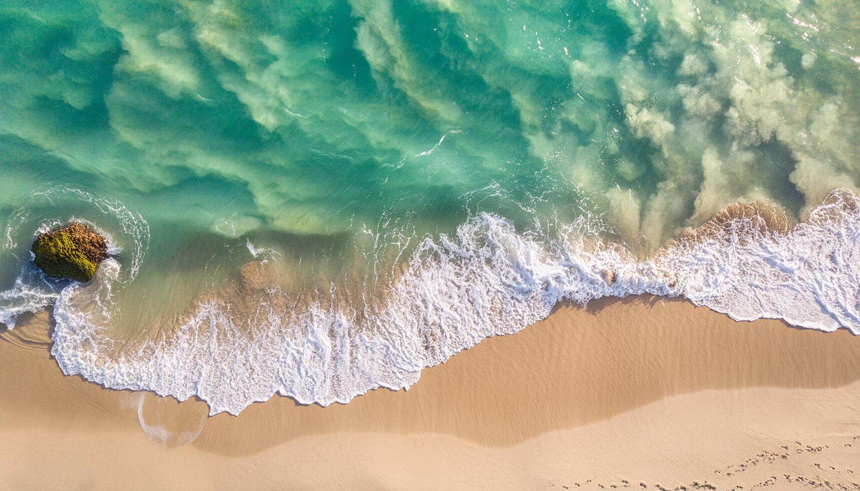 Overhead photo of crashing waves on the shoreline tropical beach