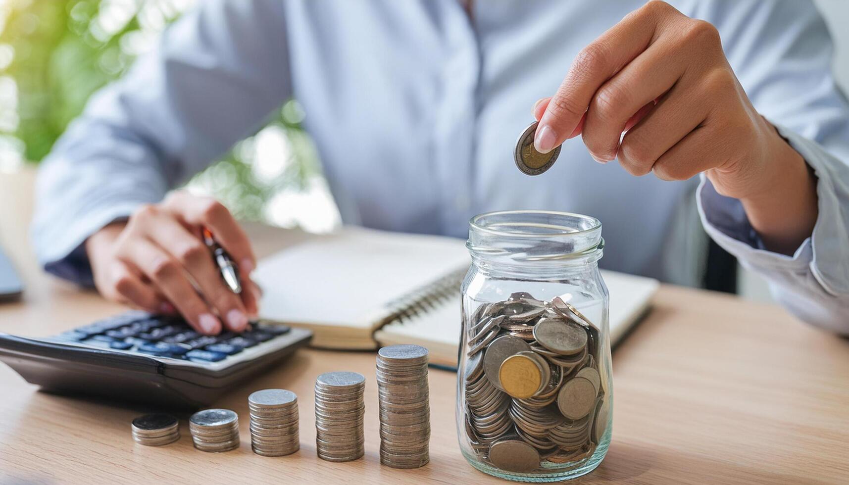 Calculate budget concept, hand putting coins in jug glass photo