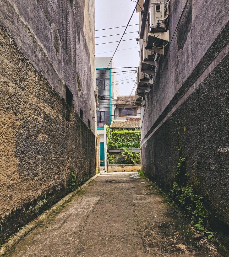 Roads in dense settlements leading to main roads are less than 2 meters wide surrounded by residential walls photo