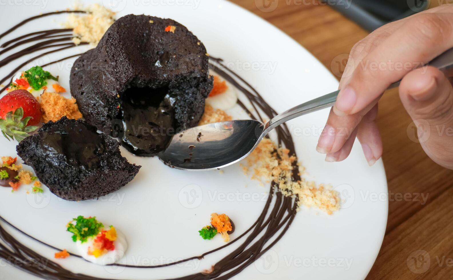 Delicious chocolate fondant or lava cake with cream, strawberry, and cake biscuit crumbles, Hot chocolate dessert pudding with liquid chocolate center, fondant au chocolate photo